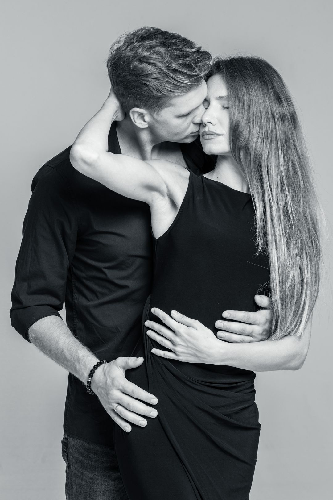 Black and white editorial portrait in a grey studio, lit from one side